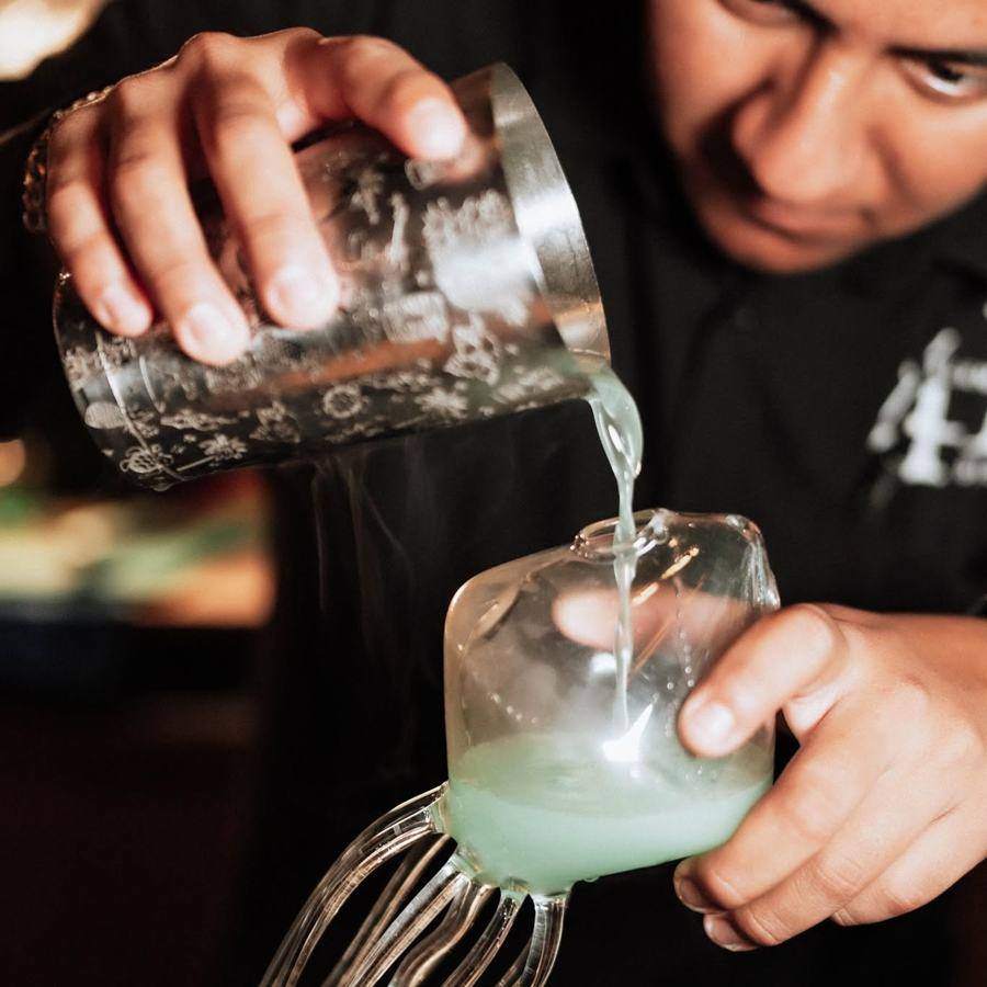 Barman sirviendo un coctel verde